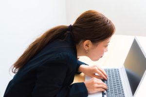 巻き肩でパソコンを操作する女性